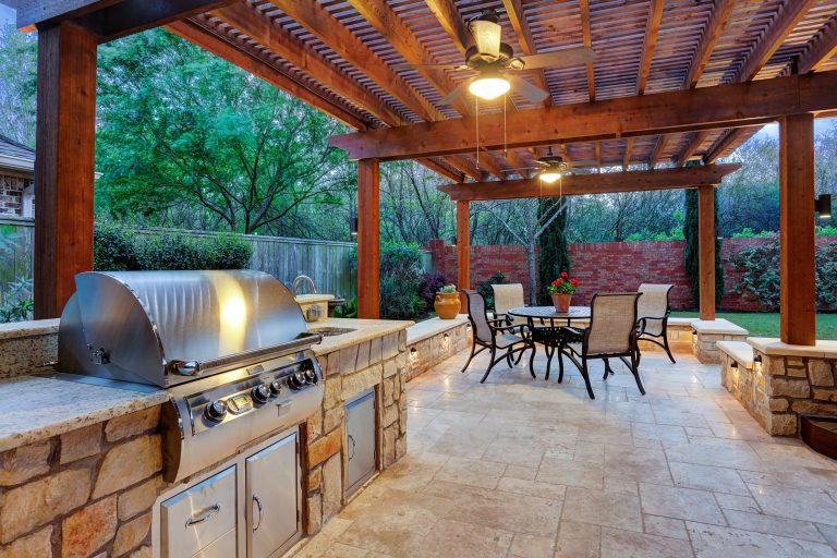 Large transitional backyard stone patio kitchen photo in Houston with a pergola