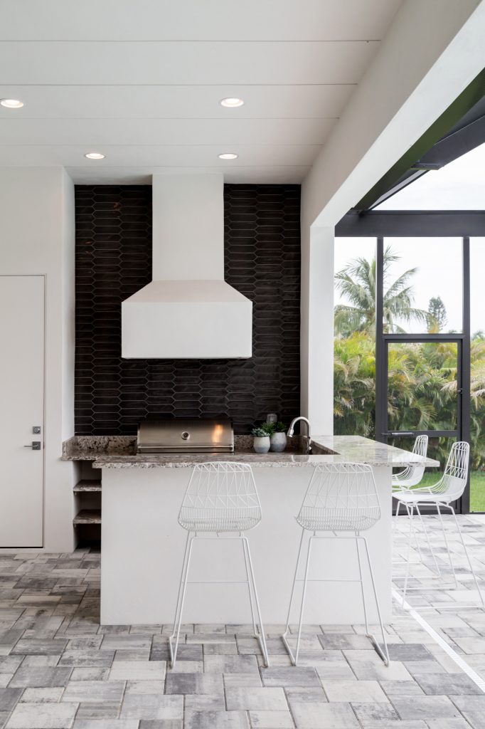 Large transitional backyard stone patio kitchen photo in Miami with a roof extension