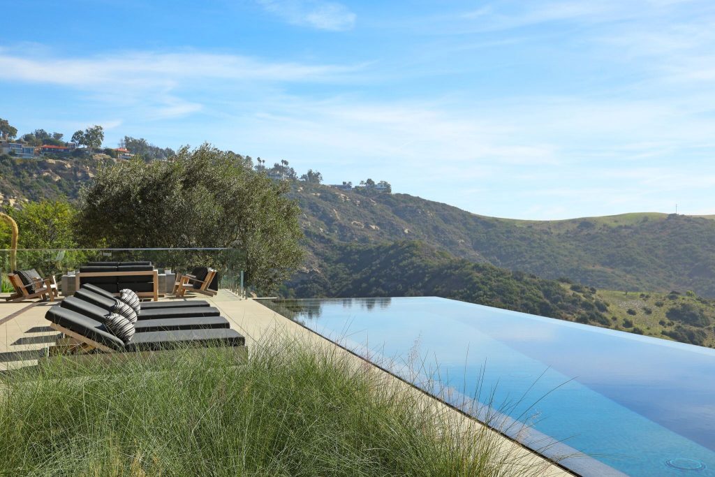 Large trendy backyard concrete paver and rectangular infinity hot tub photo in Orange County