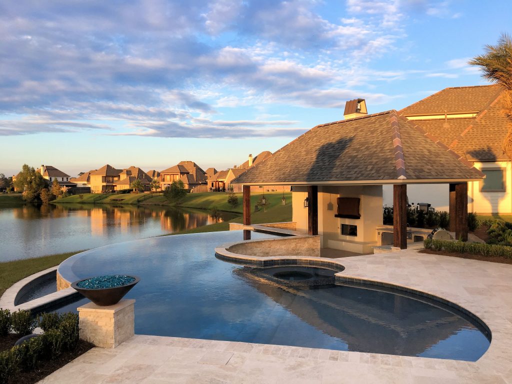 Large trendy backyard custom-shaped infinity pool house photo in New Orleans with decking