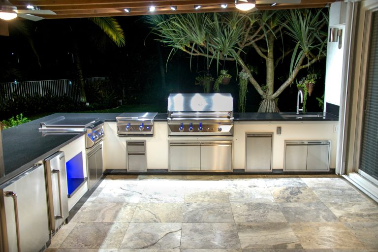 Large trendy backyard stone patio kitchen photo in Miami with a pergola