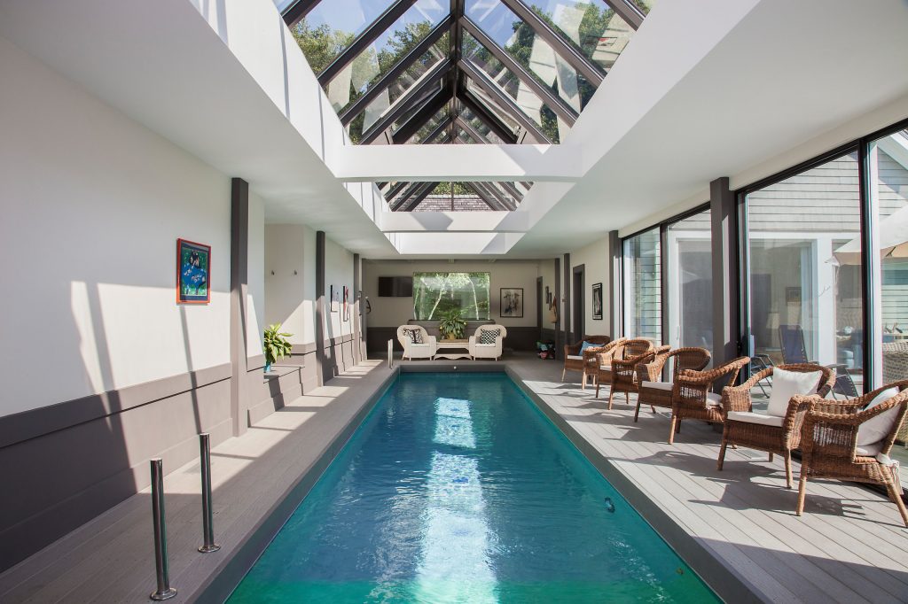 Large trendy indoor rectangular lap pool photo in New York with decking