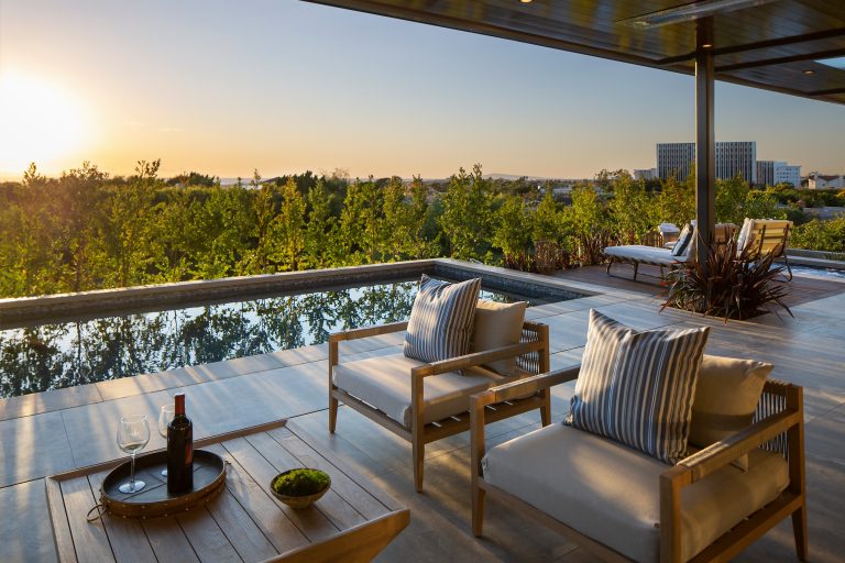 Luxurious covered wooden deck with sparkling pool and separate spa with sunset views in Orange County, California.
