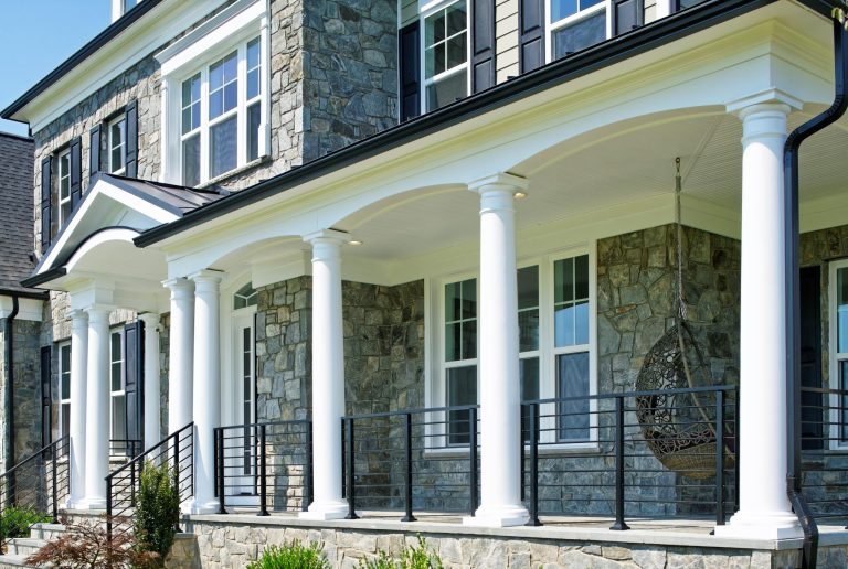 Luxurious front porch with ample space and hanging swing to enjoy idyllic views of a spacious front yard.