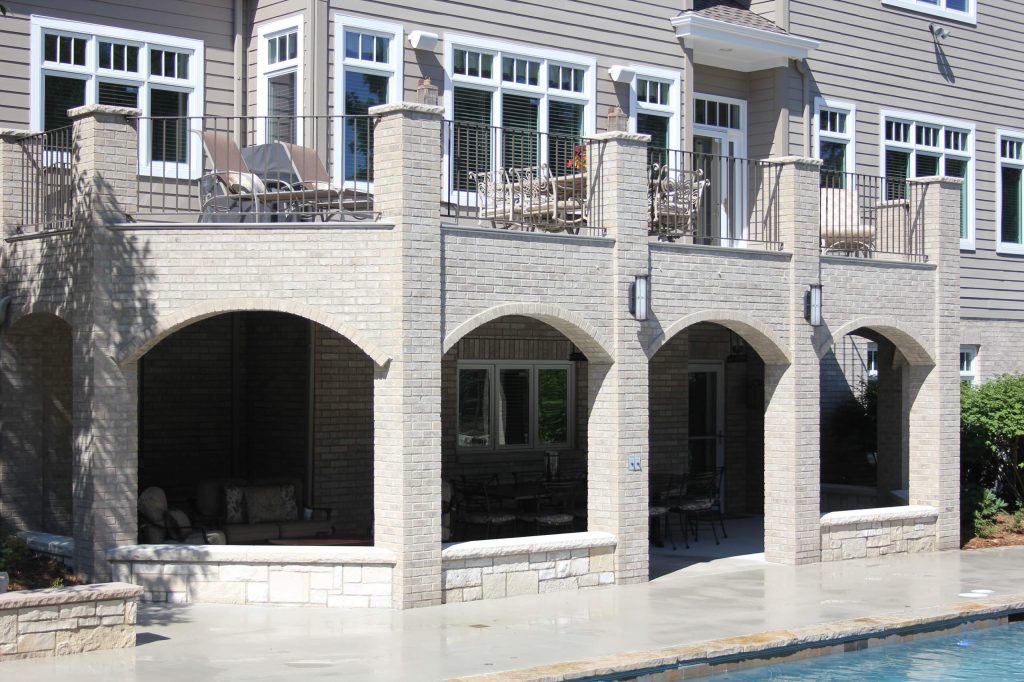 Mequon, WI Residence. Cover porch with brick arches, brick pillars and tongue and groove ceiling, top deck is composite with brick pillars and wrought iron railling. by North Shore Hardscapes | Outdoor Photos | Porch | Landscaping | Landscape Design | Outdoor Living Space | Porch Design Ideas | Outdoor Living Space Ideas | Backyard Design