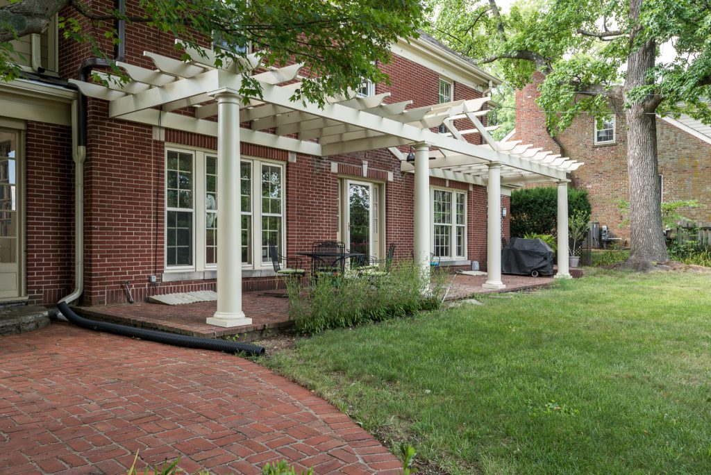 Mid-sized classic brick porch idea in Other with a pergola
