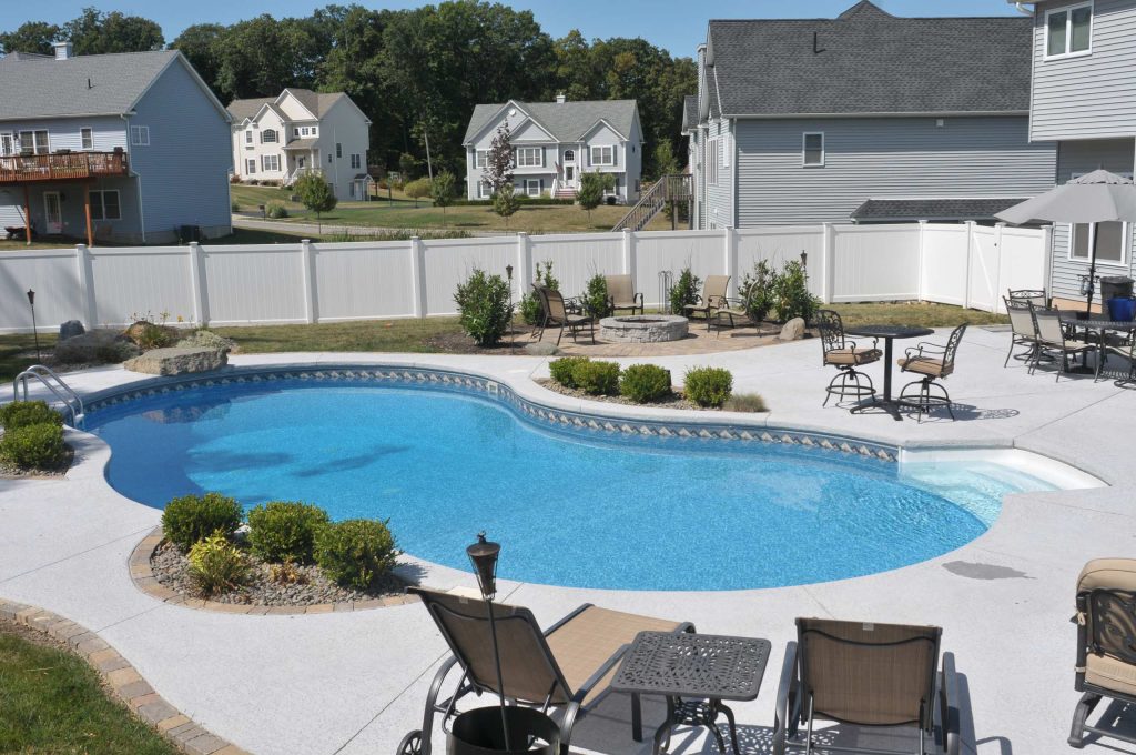 Mid-sized elegant backyard concrete and custom-shaped pool photo in New York