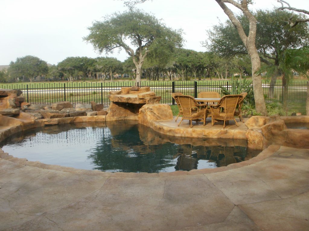 Mid-sized elegant backyard concrete and kidney-shaped lap pool fountain photo in Austin