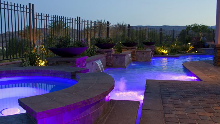 Mid-sized elegant backyard concrete paver and custom-shaped pool landscaping photo in Las Vegas
