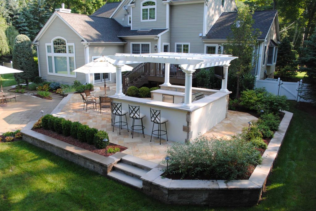 Mid-sized elegant backyard tile patio kitchen photo in New York with a pergola