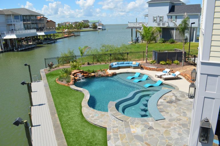 Mid-sized island style backyard stone and custom-shaped lap pool fountain photo in Houston