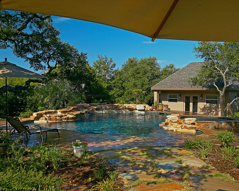Mid-sized mountain style backyard stamped concrete and custom-shaped natural pool fountain photo in Austin
