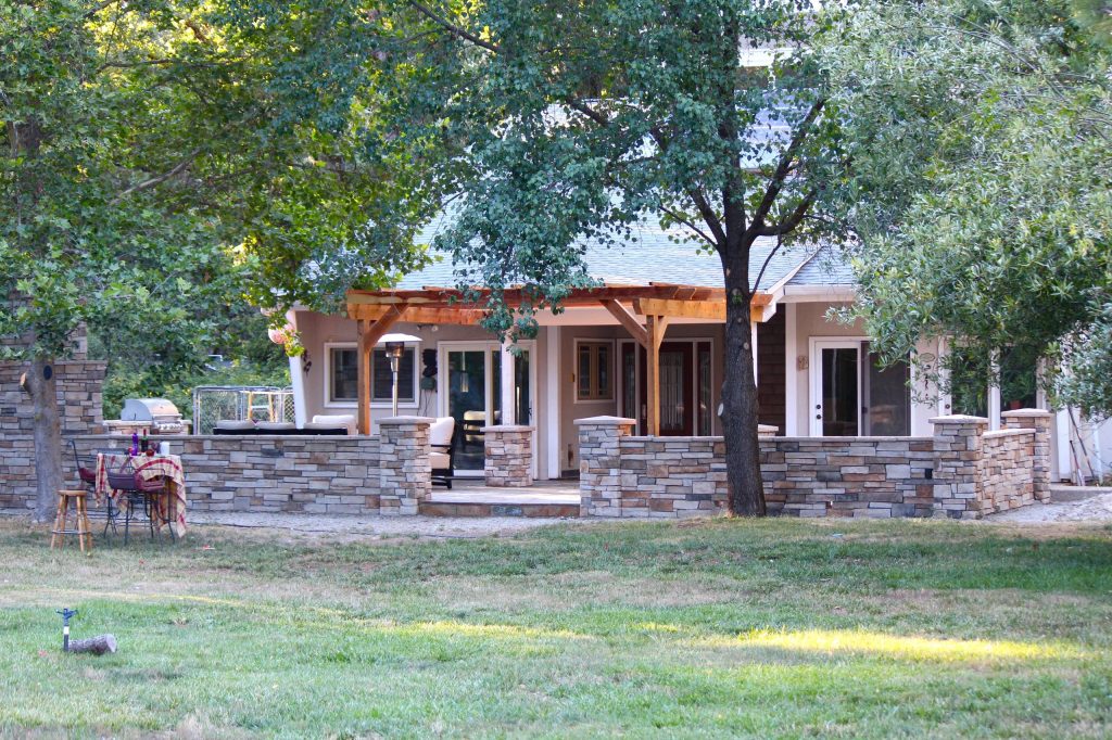 Mid-sized mountain style front yard stone patio kitchen photo in Sacramento with a pergola