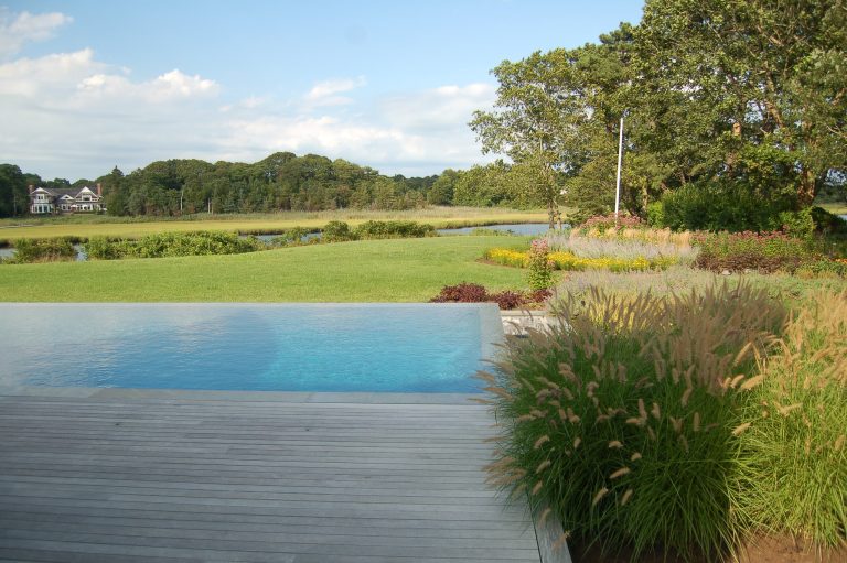 Mid-sized transitional backyard rectangular infinity pool photo in New York with decking
