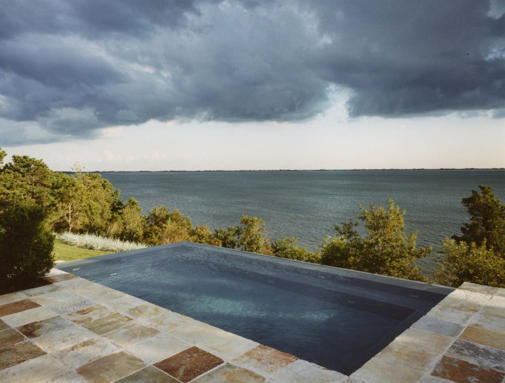 Mid-sized trendy backyard stone and rectangular infinity pool photo in New York