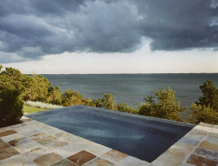 Mid-sized trendy backyard stone and rectangular infinity pool photo in New York
