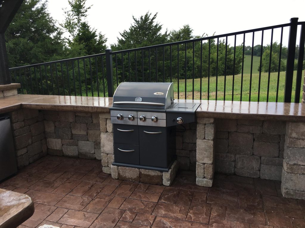 Minimalist backyard brick patio kitchen photo in Other with a pergola