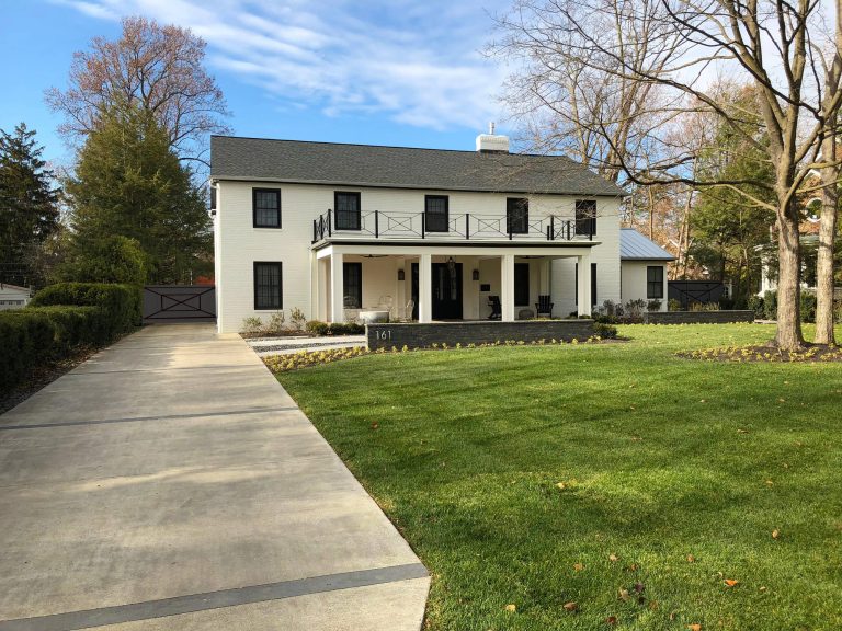 Modern farmhouse entry featuring low walls and banded buff wash driveway.