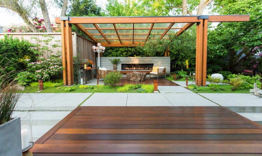 Modern landscape with an all-seasons outdoor living room. Featuring custom carpentry, gas fireplace, moss plantings, hardwood patio and hand finished concrete.