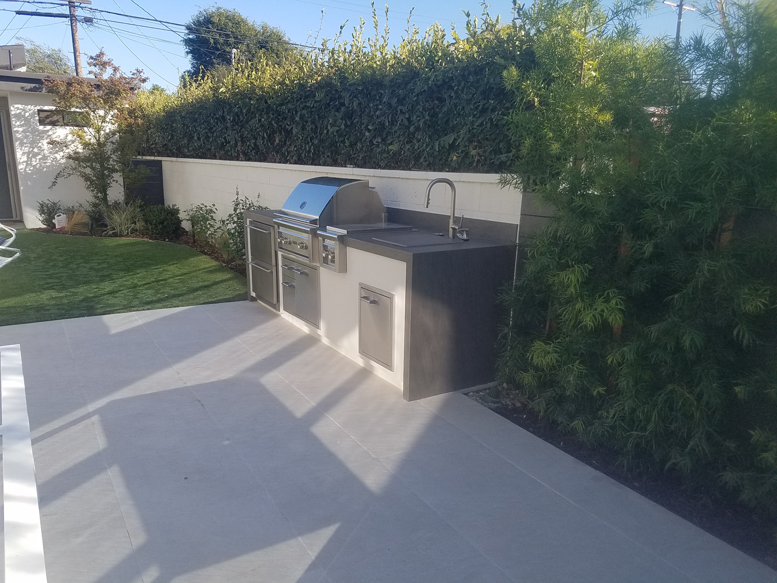 Modern outdoor kitchen with sink and custom cover
Minimalist backyard patio kitchen photo in Los Angeles