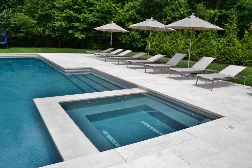 Modern outdoor pool and spa with white marble patio