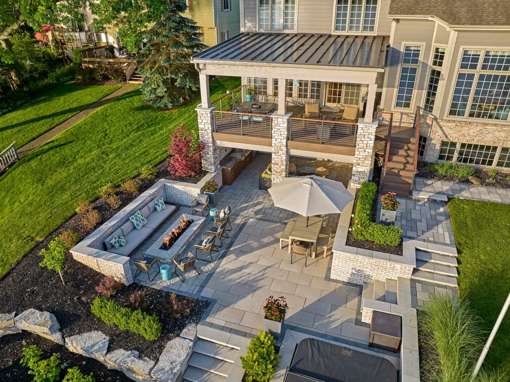 Multi-level lakeside terrace with covered outdoor kitchen, hot tub, built-in fire pit and outdoor bar