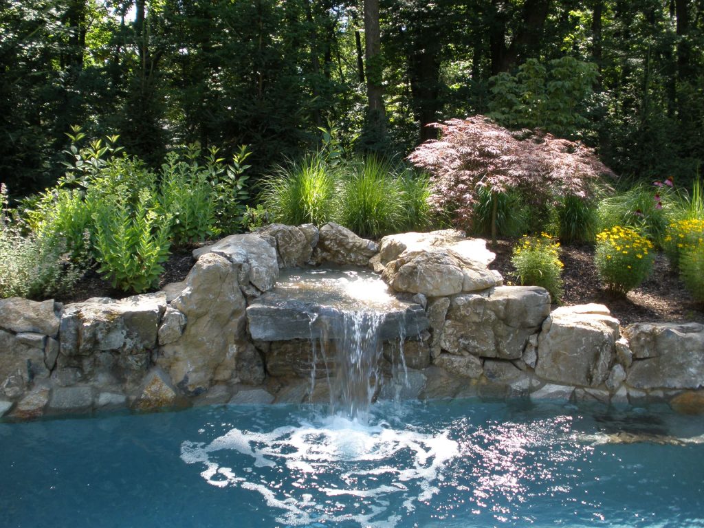 Natural Rock Waterfall with flora behind. matt meaney @ Artisan landscapes and pools