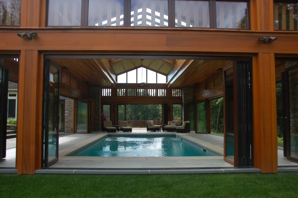 Nestled in the Berkshire Mountains, the poolhouse opens completely to the outdoors during warm months via sliding doors that fold away. In winter, swimmers can enjoy the water while watching the snow fall.