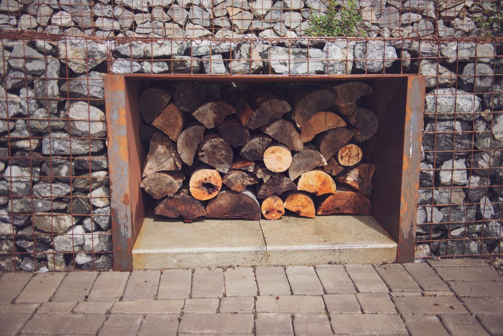 Next to the outdoor fireplace, wood is stored inside a COR-TEN steel enclosure. annacaitlinphotography.com