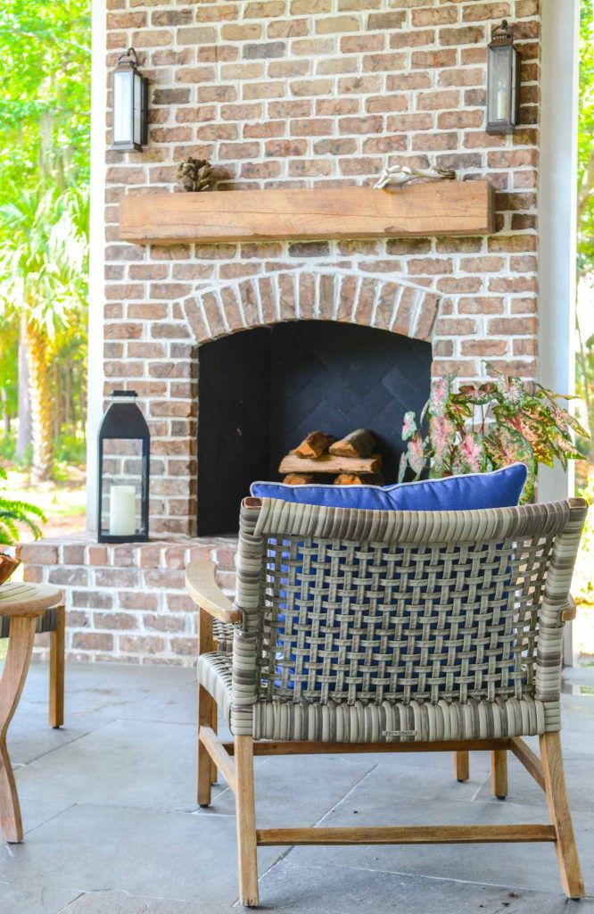 Outdoor brick fireplace with clay chimney pot topper, tabby floor, and stained pine ceiling.