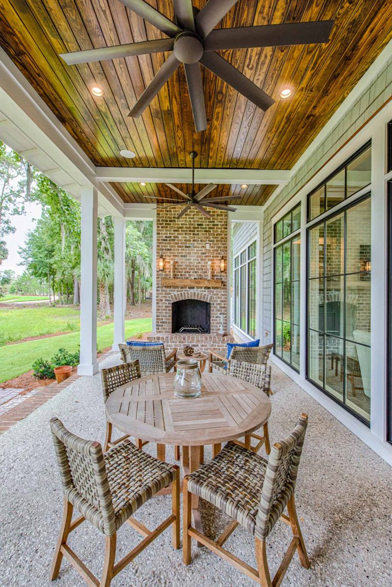 Outdoor brick fireplace with clay chimney pot topper, tabby floor, and stained pine ceiling.