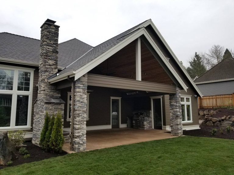 Outdoor fireplace with stone columns and outdoor living space in this new construction.