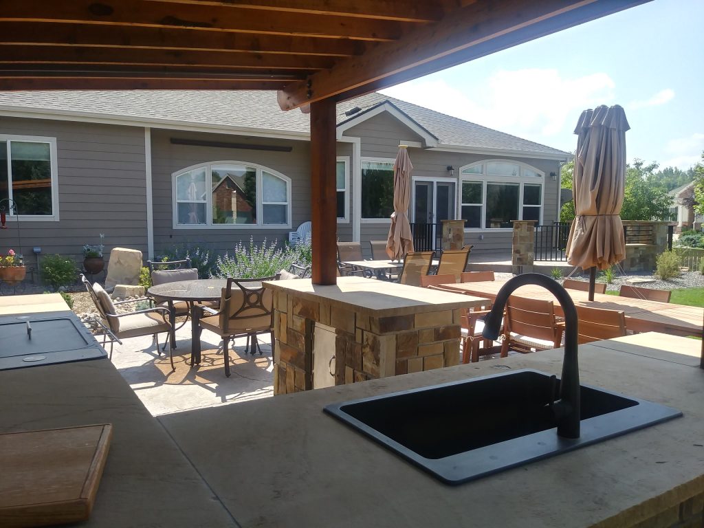 Outdoor kitchen area with sink, grill and bar area