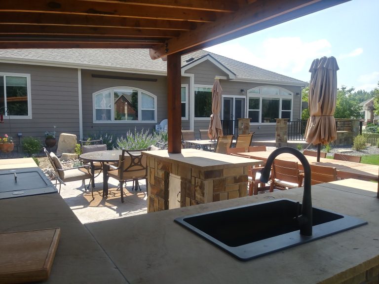 Outdoor kitchen area with sink, grill and bar area