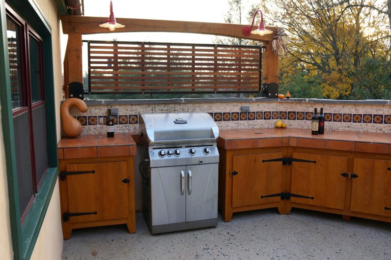 Outdoor kitchen features cypress cabinets topped with tile countertops, and a river pebble and mexican tile backsplash. Pete Cooper/Spring Creek Design