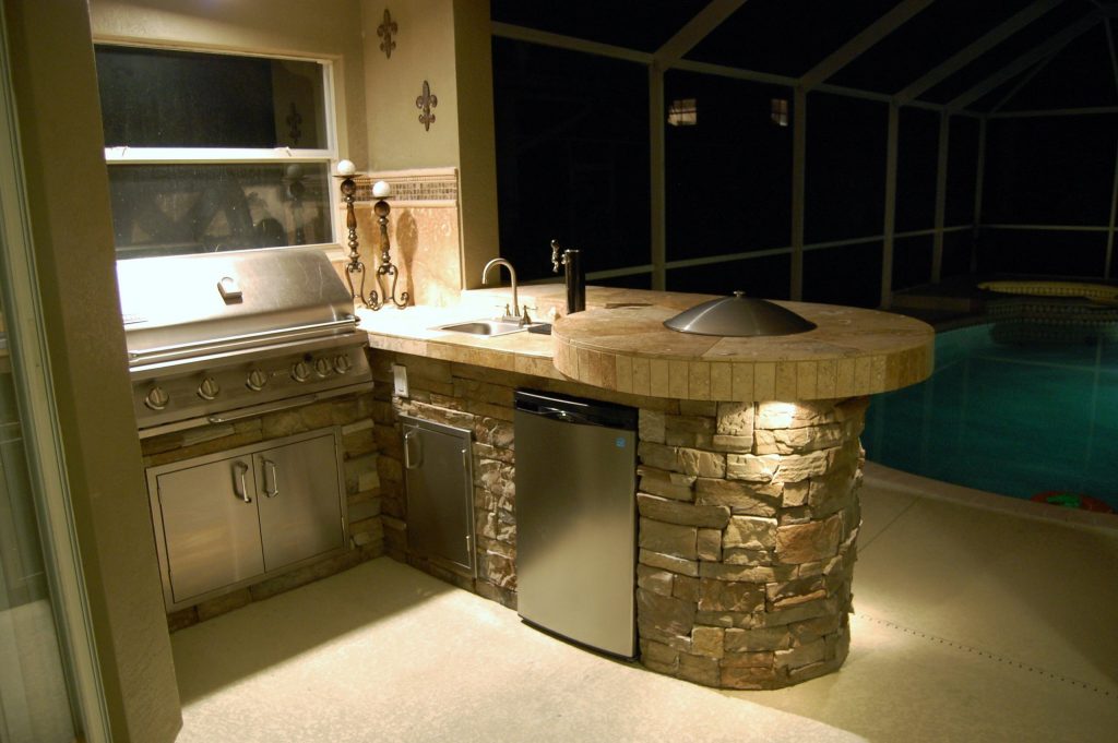 Outdoor kitchen, travertine counters, Jennifer-air grill, fire pit, accent tile, backsplash, cultured stone, under counter lights, outdoor lighting, kegerator, cool deck finish.