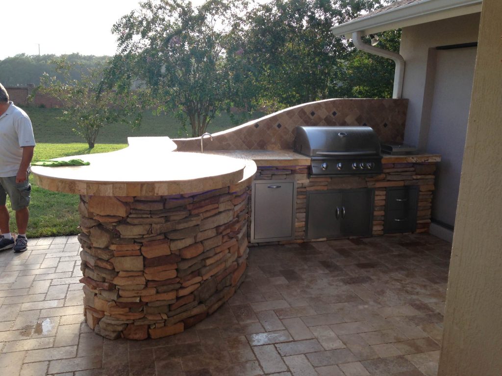 Outdoor kitchen, travertine, cultured stone, rustic southern ledge stone, backsplash, sink, undercounter fridge, curved island, raised bar top, travertine pavers, grill, side burner