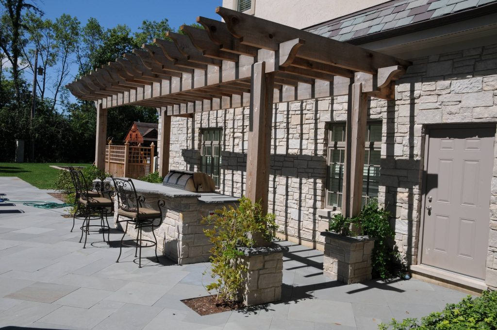 Outdoor kitchen with bar seating, along with a 42" Wolf grill.