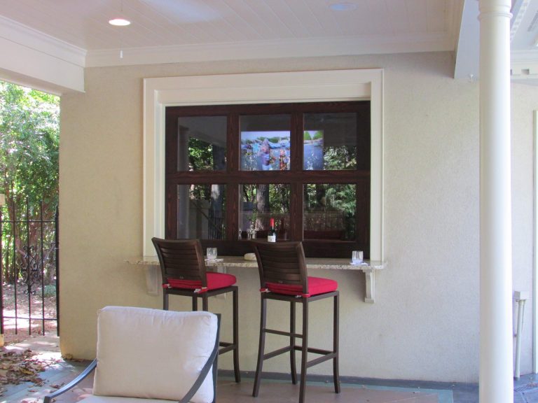 Outdoor living area transformed from builder grade to luxury living area. Roll up door encloses the bar and wall mounted television. Use this area any time of the year. Photo credit -Ray Sheedy