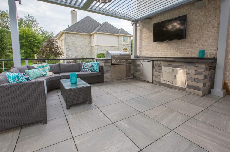 Outdoor living space in Fishers, Indiana designed and installed by Aspen Outdoor Designs. Outdoor kitchen area on a porcelain tile deck with seating for entertaining.
