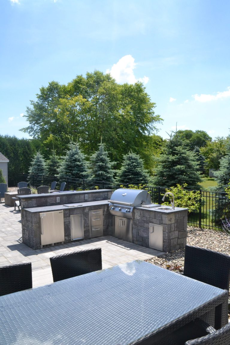Outdoor living space with lounge seating, masonry kitchen and raised bar top seating