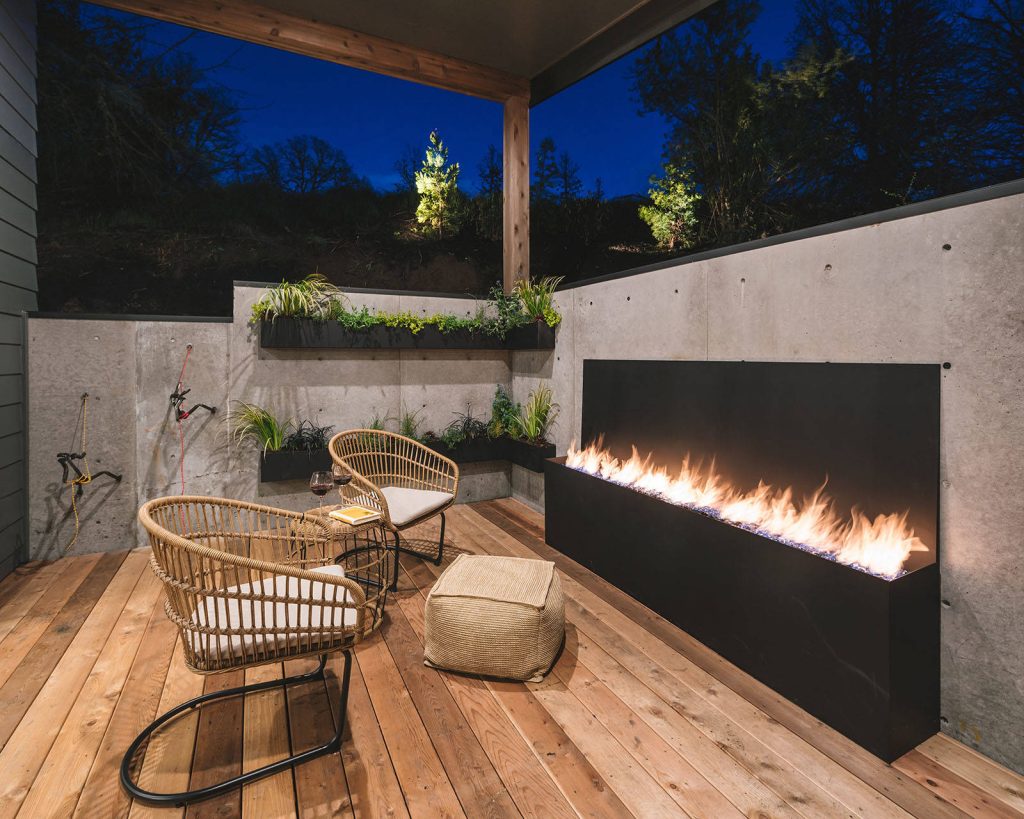 Outdoor patio with gas fireplace that lives right off the kitchen. Perfect for hosting or being outside privately, as it's secluded from neighbors. Wood floors, cement walls with a cover.