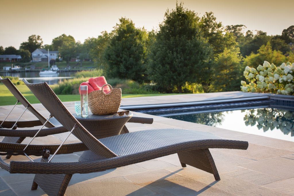Outdoor pool with lounge chairs and water views. David Burroughs