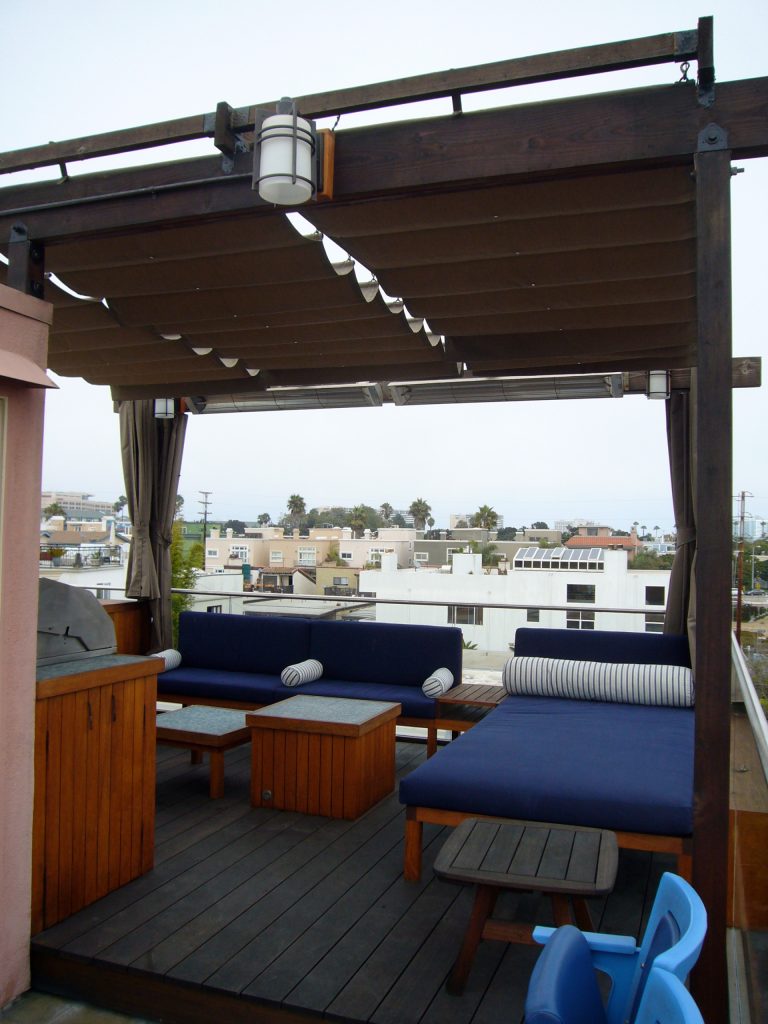 Outdoor roof deck with glide-by-wire roman shade canopy, teak furniture including day-bed, bench, tables and cabinets with built-in barbecue grill and fire pit