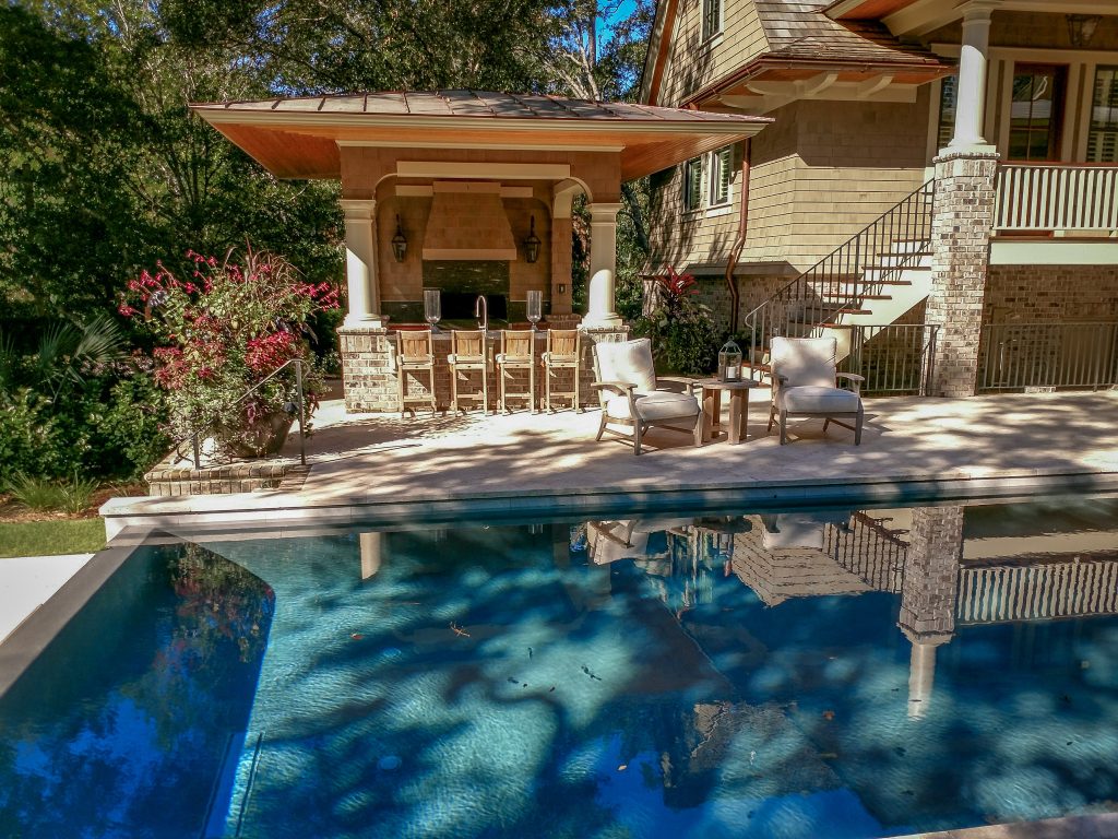 Patio kitchen - coastal stone patio kitchen idea in Charleston with a pergola