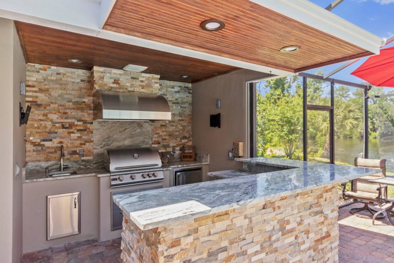Patio kitchen - contemporary stone patio kitchen idea in Orlando with a roof extension