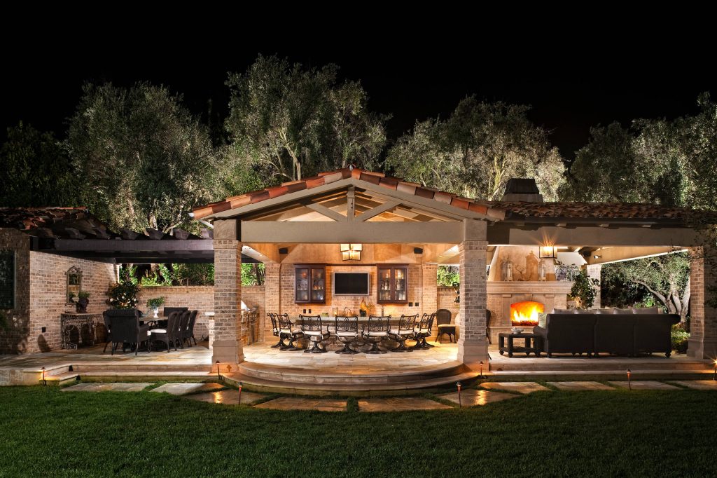 Patio kitchen - huge mediterranean backyard stone patio kitchen idea in Orange County with an awning
