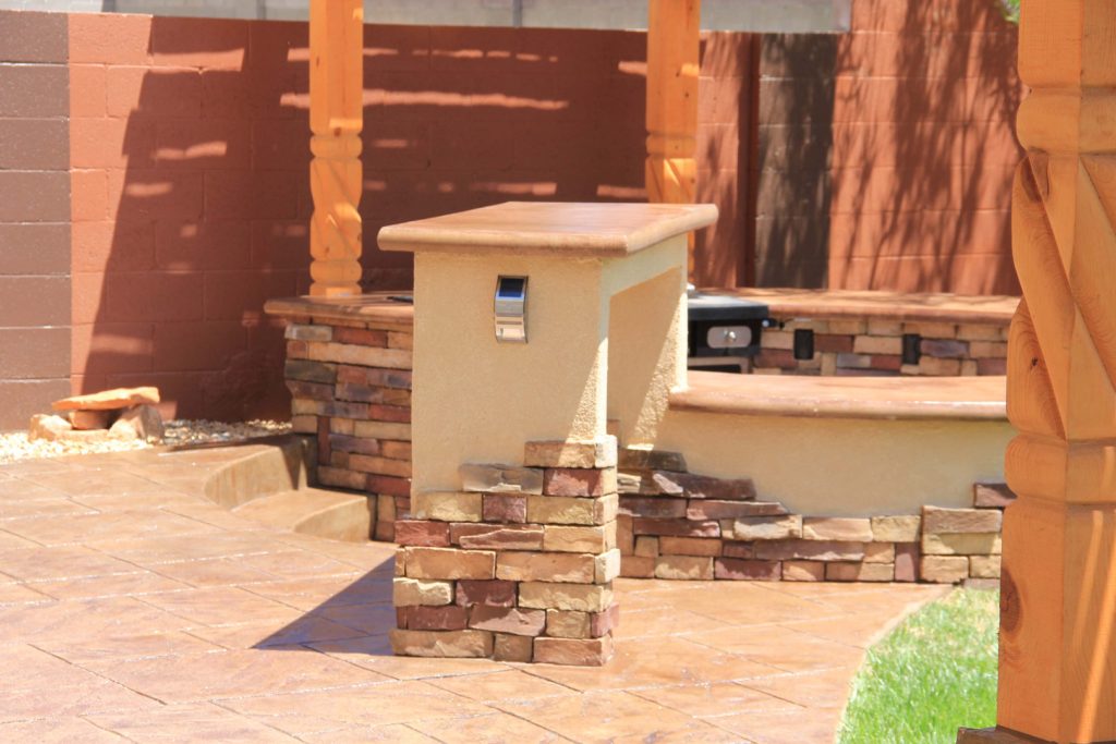 Patio kitchen - large backyard stamped concrete patio kitchen idea in Albuquerque with a pergola