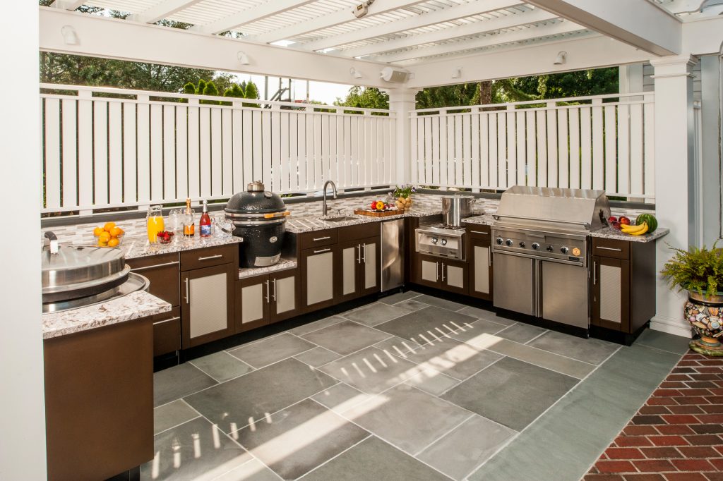 Patio kitchen - large contemporary backyard brick patio kitchen idea in New York with an awning