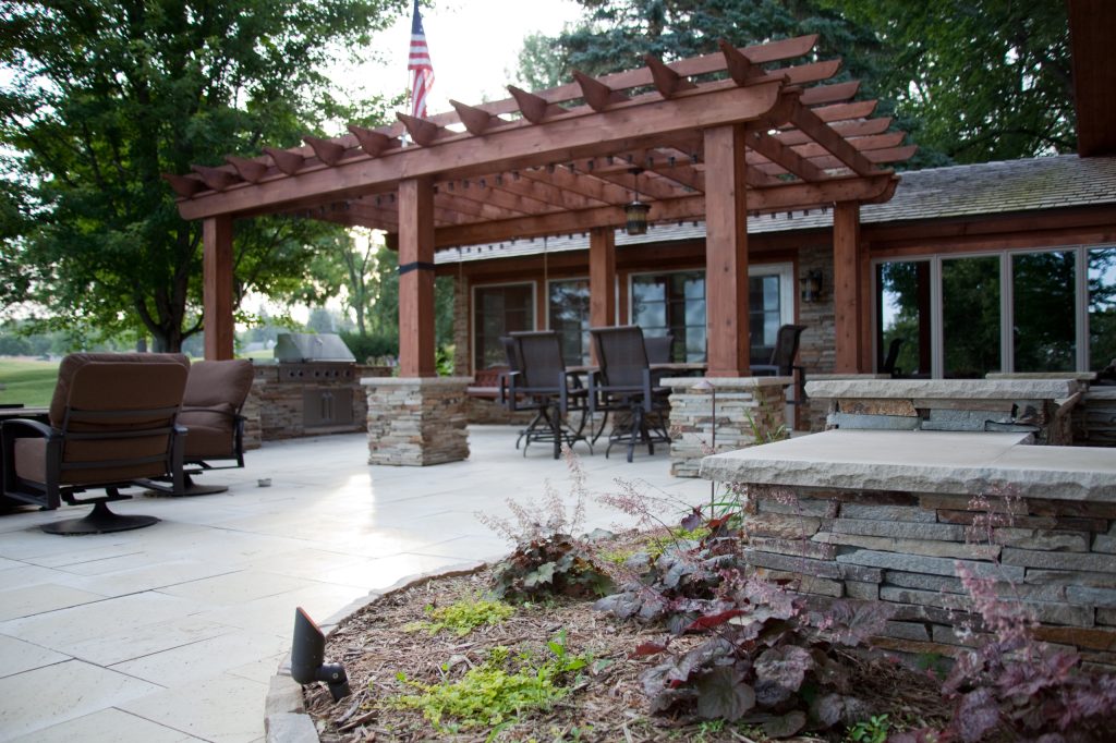 Patio kitchen - large contemporary backyard stone patio kitchen idea in Other with a pergola